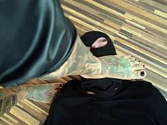 Татуирана възрастна жена доминира над своя роб на краката си в горещо босо видео